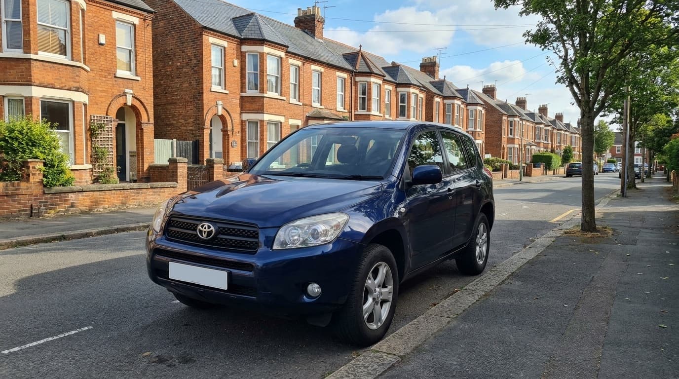A dark blue Toyota RAV4 parked on a tree-lined UK street